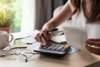 Woman calculating expenses with a calculator at a desk