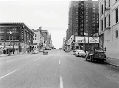 Vintage city street view with buildings cars and signage in black and white