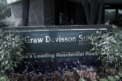 Real estate office sign with surrounding greenery