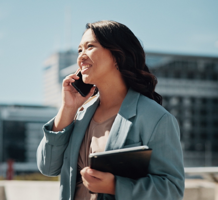 Businesswoman in blue blazer talks on cellphone outside office building