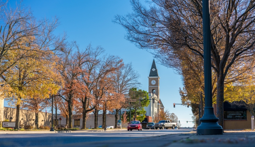 Clock tower with autumn trees lining a sunny street in a small town