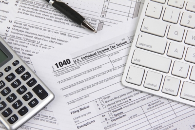 Calculator pen and keyboard on US 1040 tax return forms desk scene