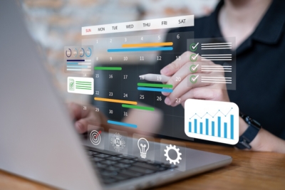 Person using a laptop with digital calendar and graphs on screen