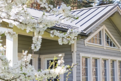 Gray timber house with white trim and blossoming cherry branches in the foreground