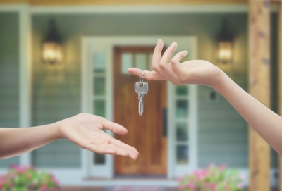 Handing over house keys in front of a home porch