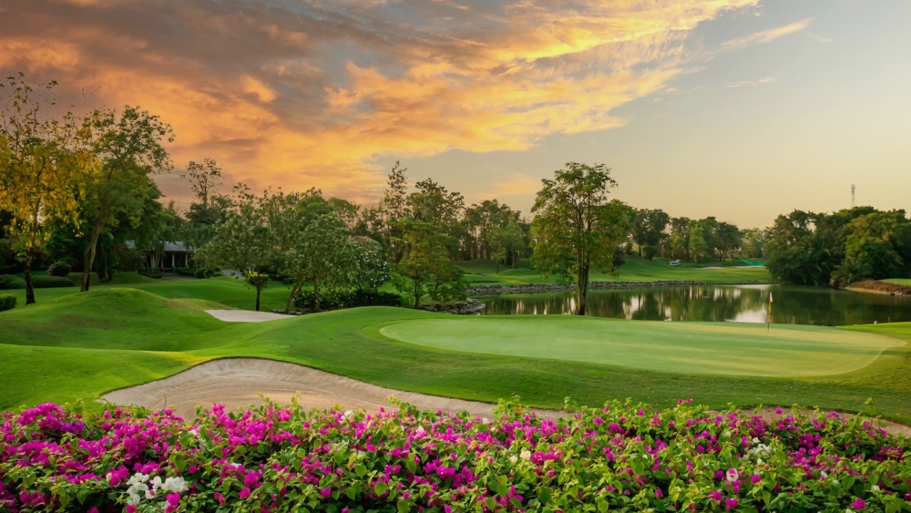 Scenic golf course at sunset with vibrant flowers and lush greenery
