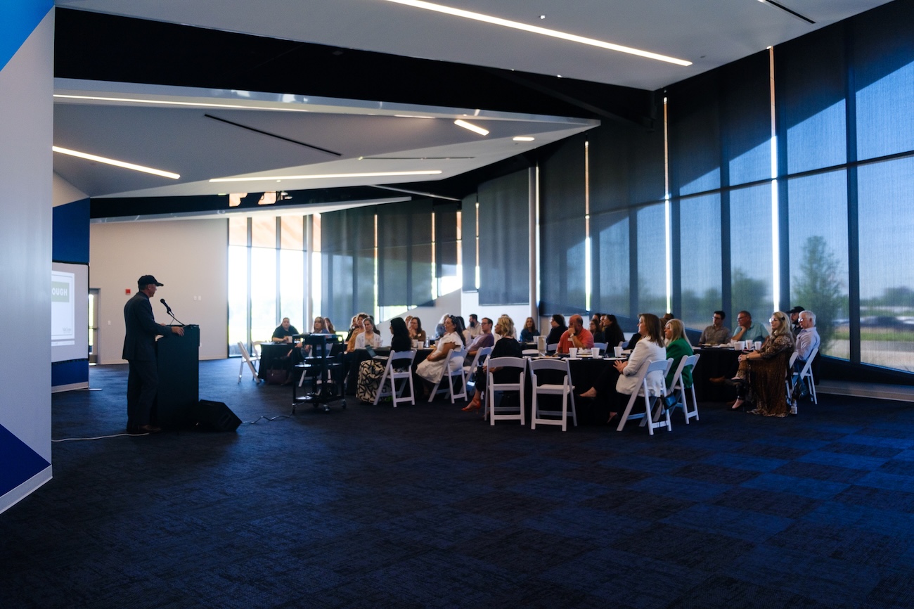 Business presentation in a modern conference room with an audience seated at tables.