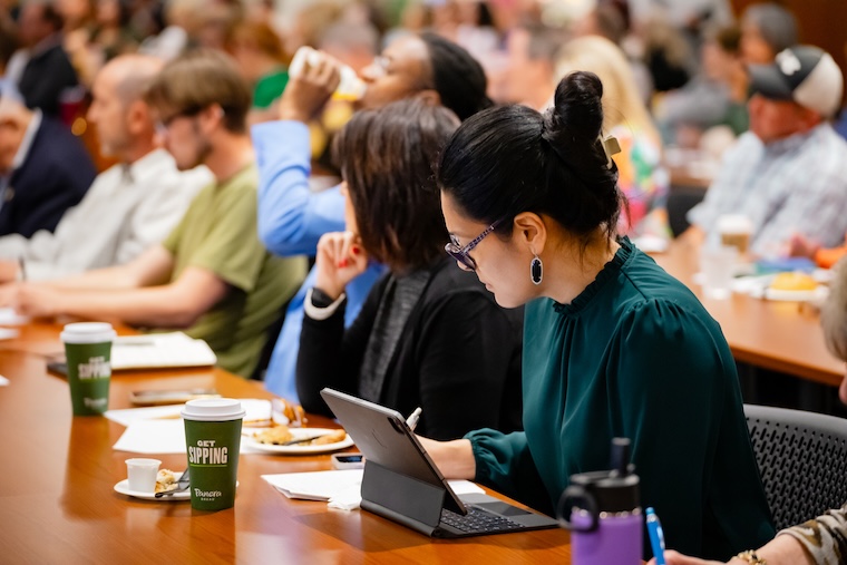 Woman taking notes on tablet in crowded seminar room
