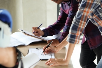 Engineers reviewing blueprints and taking notes during a construction planning meeting