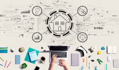 Person working on real estate project at desk with house icon and graphics in background